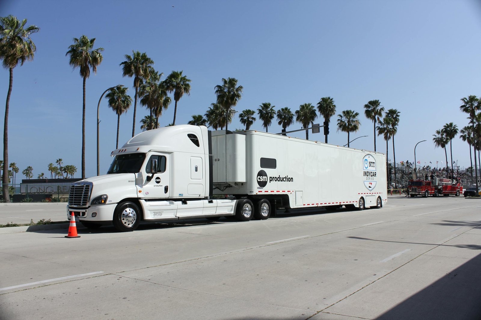 A large white truck parked on a sunny day in Long Beach, CA, with palm trees and blue sky.