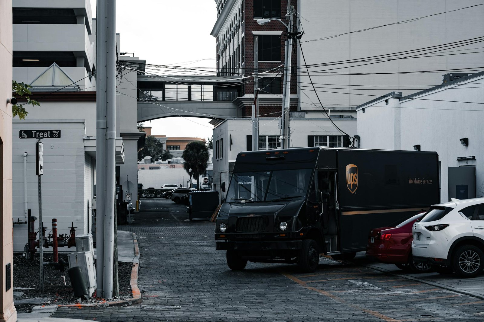 A UPS truck parked in an urban alleyway surrounded by buildings and parked cars.